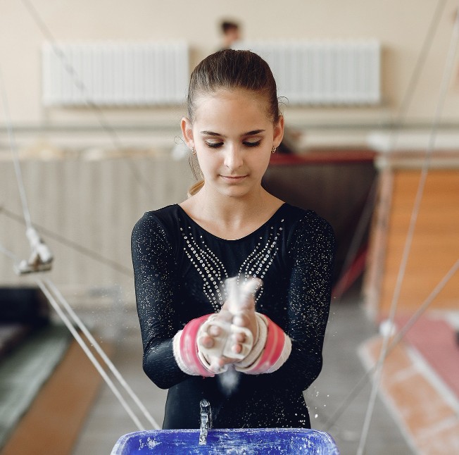 Competitive gymnast chalking her hands before training